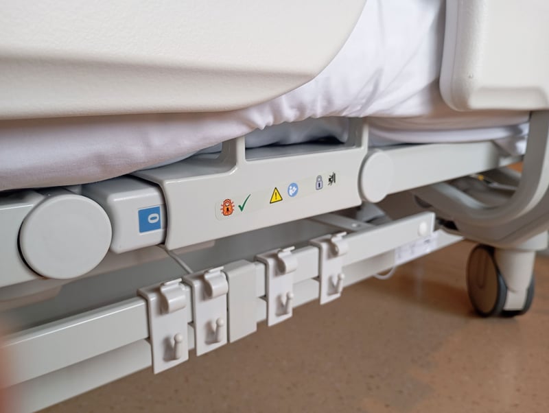 The underside of a hospital bed up close to where only the frame itself is in view. The underside of a hospital bed up close to where only the frame itself is in view.